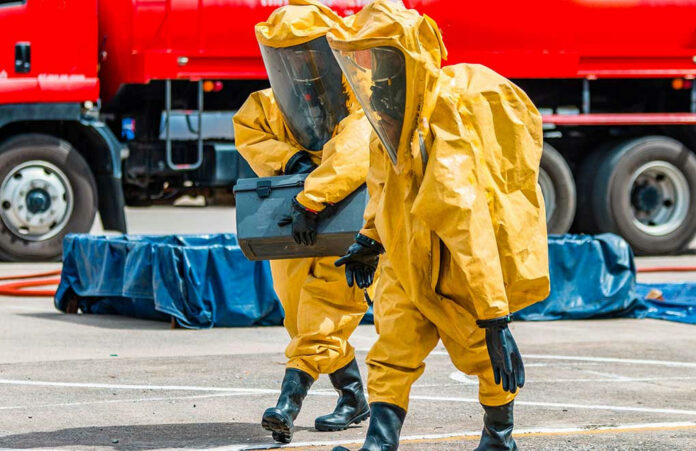 1110628994 Workers in hazmat suits carrying a black container.