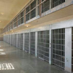 Prison Gender Clash Explodes in Scotland Empty prison cell block with barred doors and walkway.