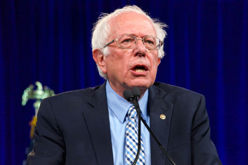 shutterstock_1486814015 Bernie Sanders speaking at an event, wearing a suit.