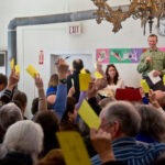 Classroom Kissing Scandal Erupts People holding up voting cards at a meeting.