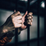Iran’s Latest Executions Target Young Protesters Hands gripping prison bars, suggesting confinement