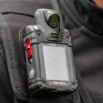 How The Checkout Counter Became a Deadly Crime Scene Close-up of a body camera attached to a persons shoulder
