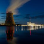 The Nuclear Shutdown Green Activists Didn’t Expect Nuclear power plant at night with cooling tower and smoke rising