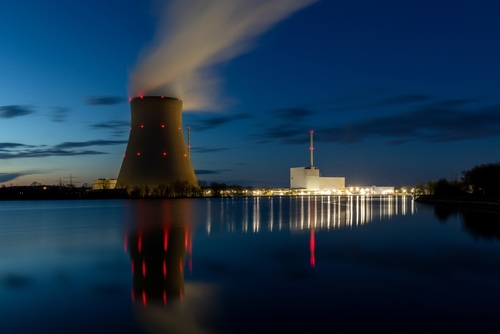 Nuclear power plant at night with cooling tower and smoke rising