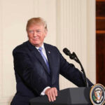 Trump Dares CNN: Go ‘Normal’ Person speaking at podium, presidential seal on front.