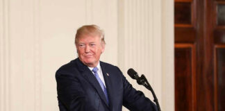 Person speaking at podium, presidential seal on front.