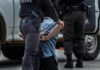 Spy Dragnet Shocks Lebanon Police officer arresting and handcuffing a person.