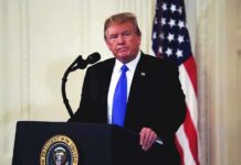 man at podium with microphone and US flag