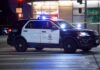 Police SUV blocks an intersection at night with lights flashing