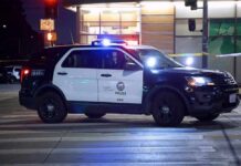 AI Slip-Up Triggers Armed Stops Police SUV blocks an intersection at night with lights flashing