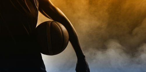 shutterstock_437181640-1 Basketball player silhouette with a ball in hand.