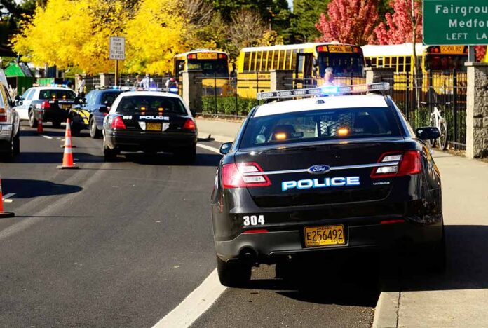 Police cars and school buses on a sunny street.