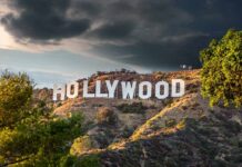 Hollywood sign on hills under cloudy sky.