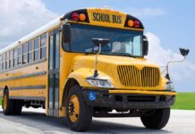 Yellow school bus on road under cloudy sky.