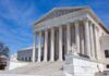 Supreme Court building with columns and statues outside.