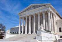 Supreme Court building with columns and statues outside.