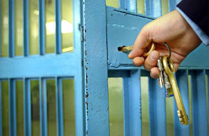 Hand unlocking a metal gate with keys.