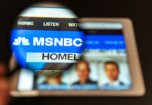 Magnifying glass over tablet displaying MSNBC homepage.