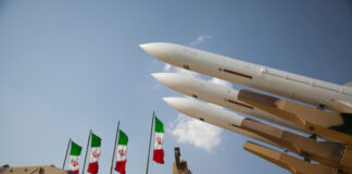 Missiles on launchers beside Iranian flags.