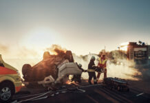 Firefighters responding to a car crash at sunset.