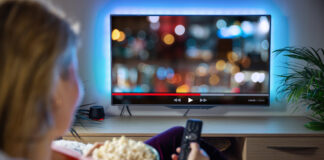 Person watching TV with bowl of popcorn.