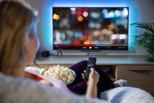 Person watching TV with bowl of popcorn.