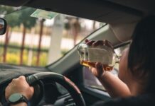 Person drinking alcohol while driving a car.