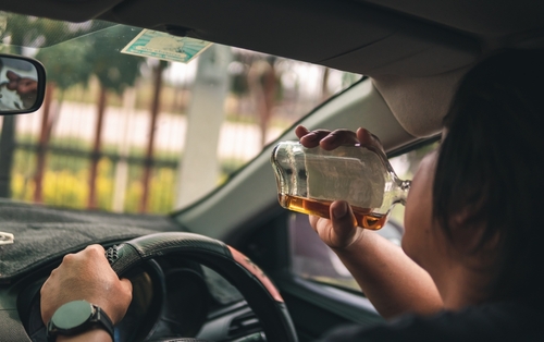 Person drinking alcohol while driving a car.