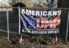 Americans for Trump banner on a fence with flags