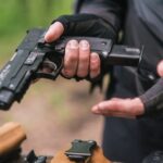 Person holding a pistol, wearing tactical gloves.