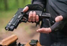 Person holding a pistol, wearing tactical gloves.