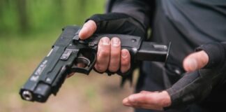 Person holding a pistol, wearing tactical gloves.