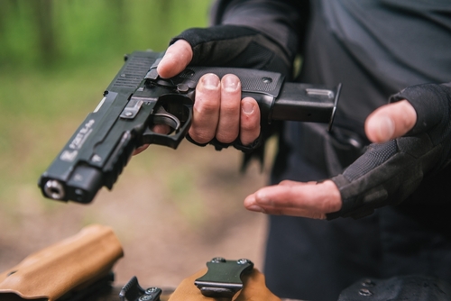 Person holding a pistol, wearing tactical gloves.