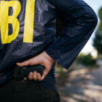 FBI agent holding a gun behind their back.