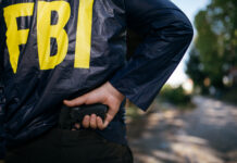 FBI agent holding a gun behind their back.