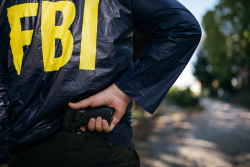 FBI agent holding a gun behind their back.